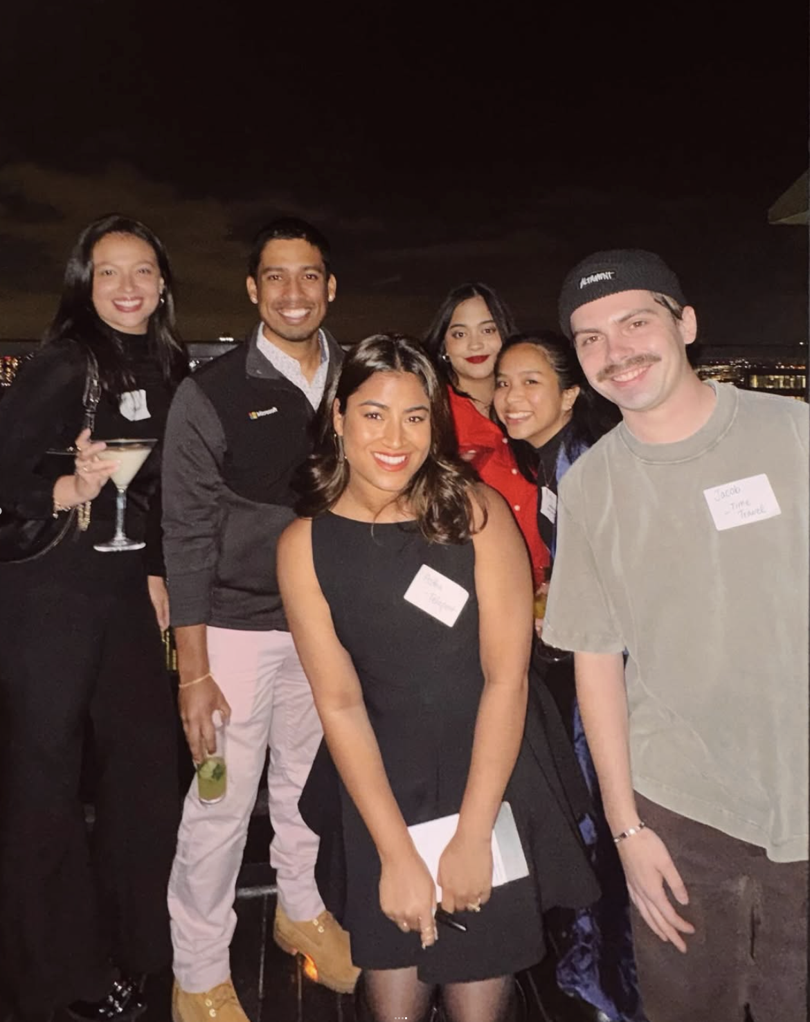 A small group of designers laughing together on the rooftop at night