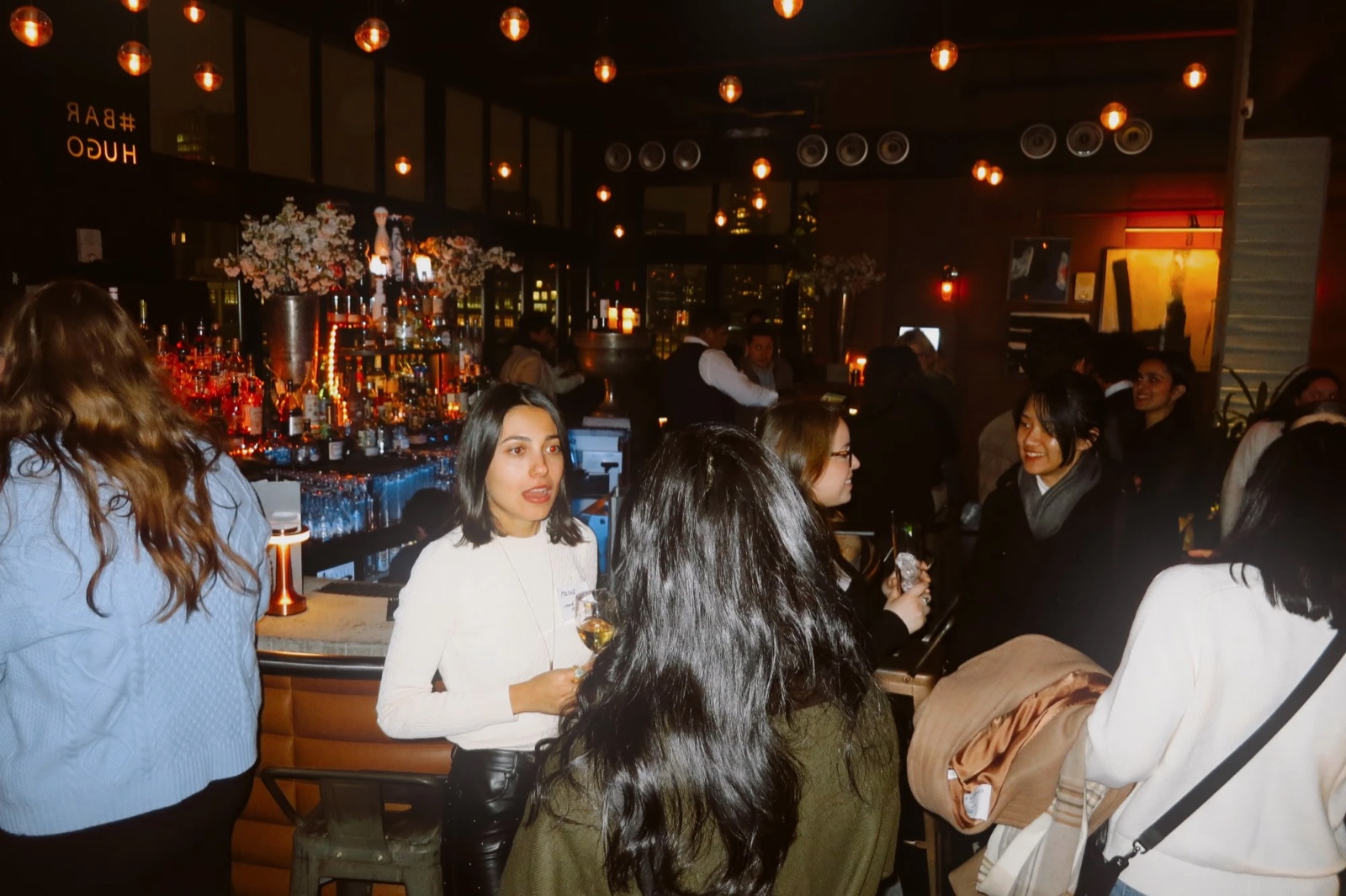 Designers chatting at the bar at Bar Hugo under glowing pendant lights