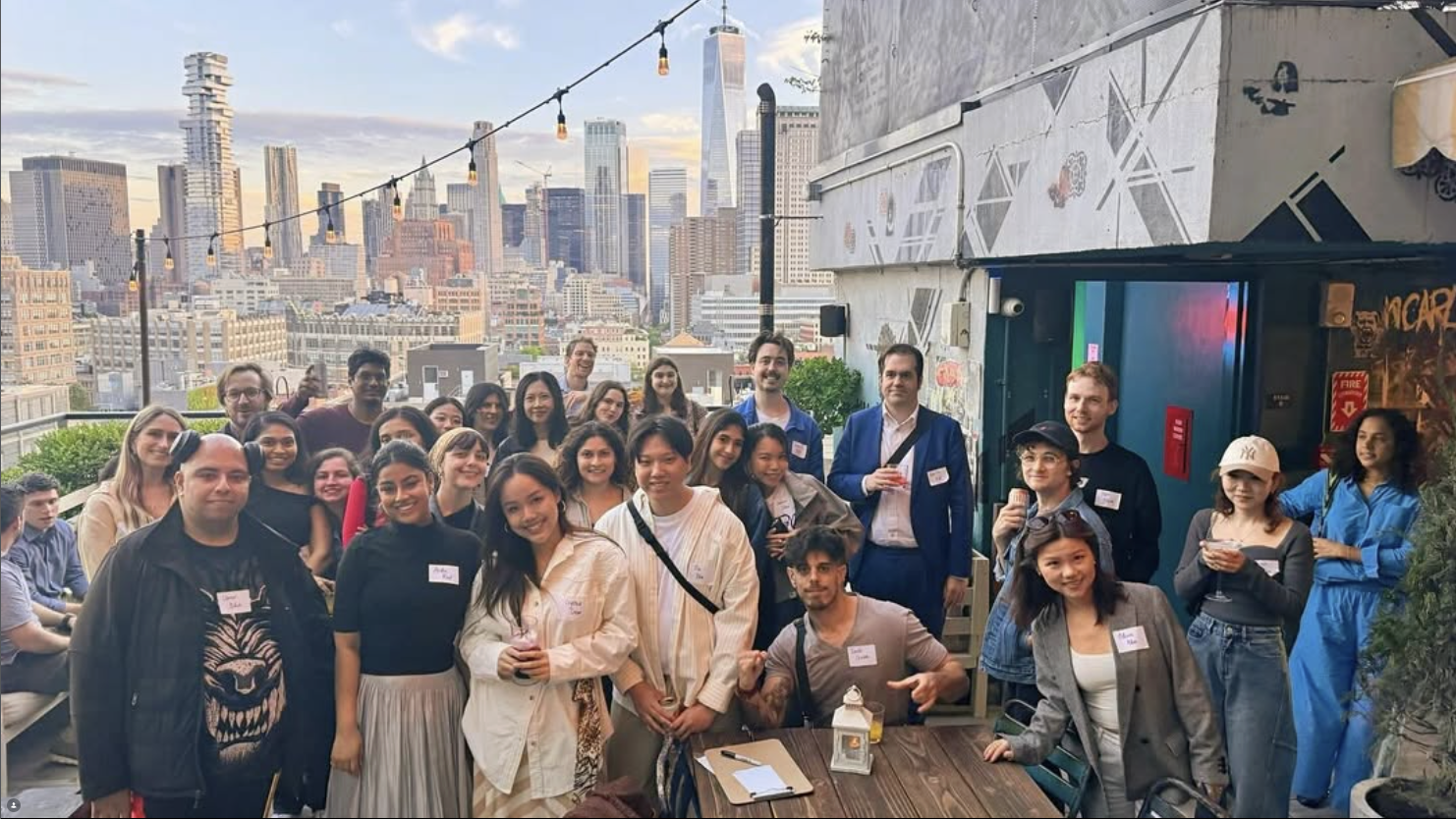 A rooftop group photo at golden hour with the Manhattan skyline behind